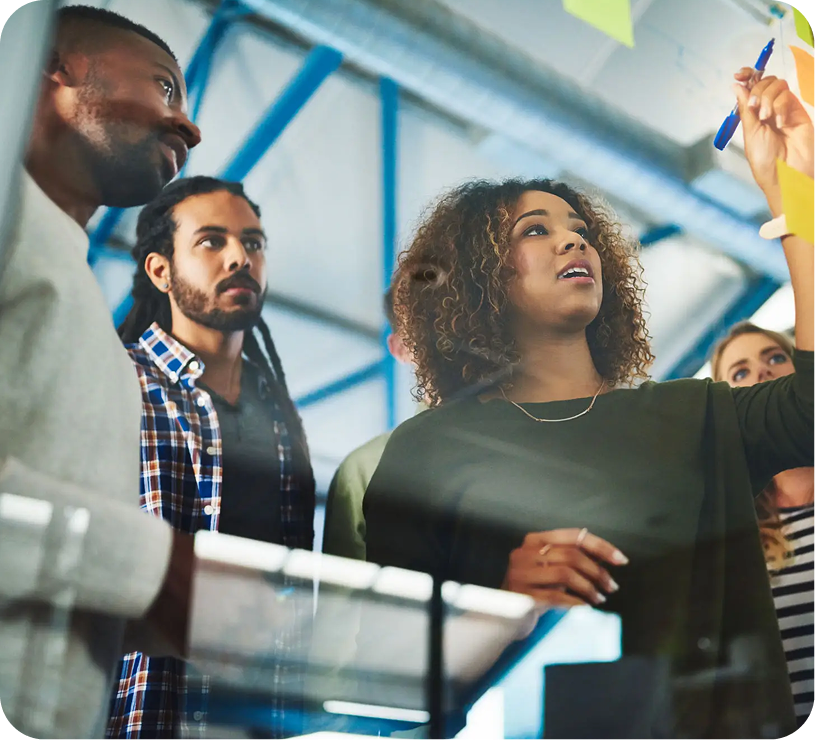 A diverse group collaborates around a whiteboard in a modern office.