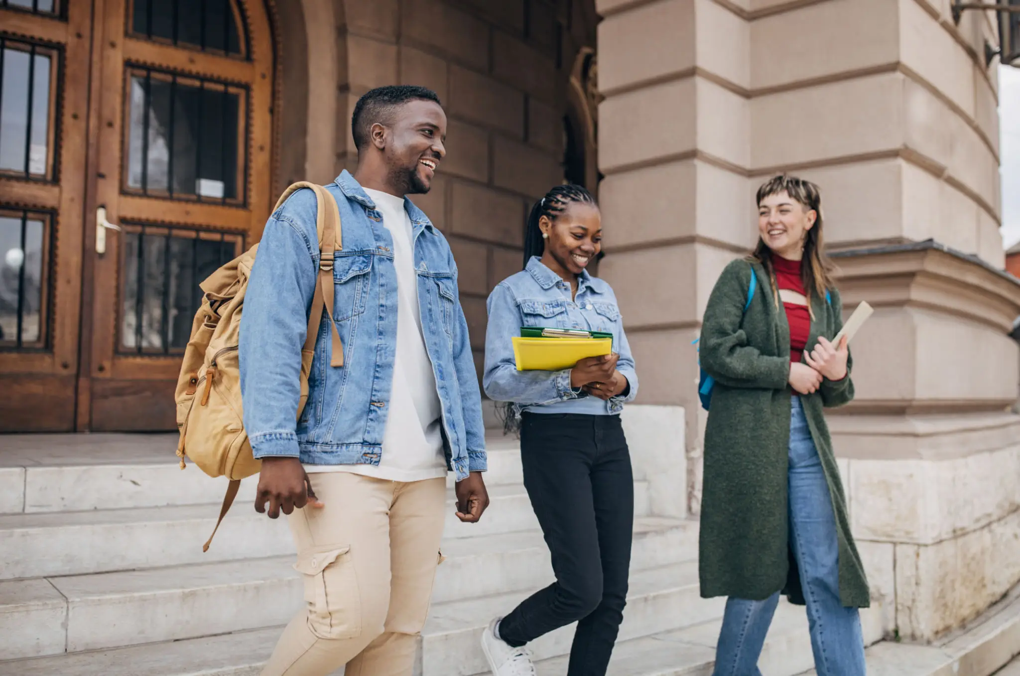 Three friends joyfully walking outside a historic building.